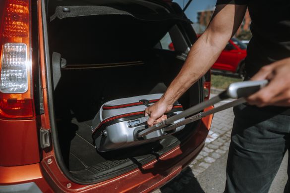 Man putting suitcase in the boot of a car