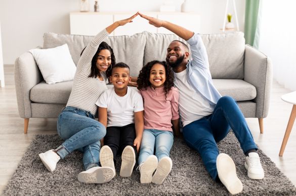 Family sitting on floor with parents touching hands above head