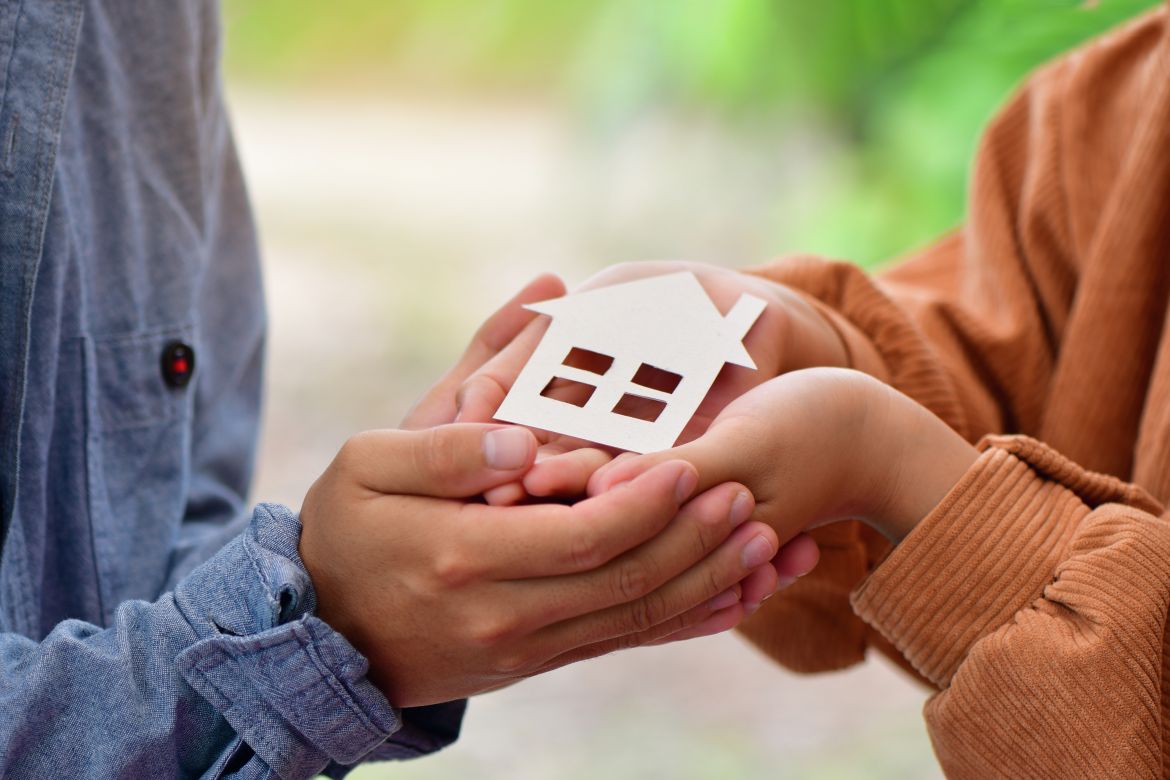 Hands holding paper cutout of house